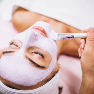 Cosmetologist applying mask on a face of client in a beauty salon